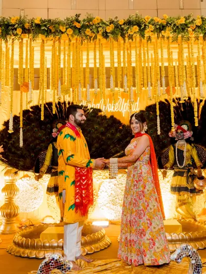 A beautiful shot of the couple on their Haldi stage, surrounded by performers and grand decor.