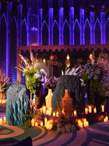 An artful installation of candles, florals, and textured rocks set against a backdrop of Gothic arches, creating a mystical focal point for the Sufi night.