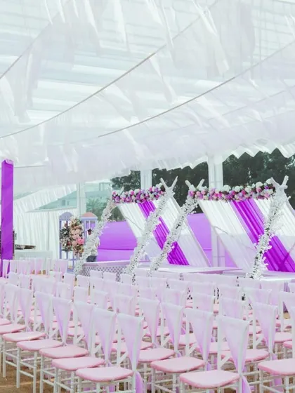 The guest seating arrangement for the carnival, with chairs decorated in alternating pink and white, under a large white tent.