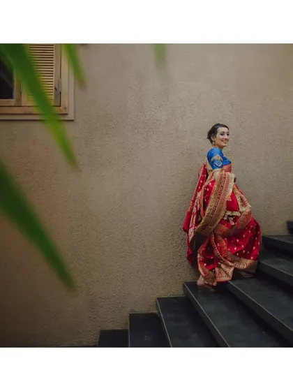 The bride ascending a staircase, her red and blue sari creating a beautiful splash of color.