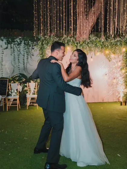 The couple's first dance under a curtain of fairy lights, a romantic and magical moment captured with a sense of movement and joy.