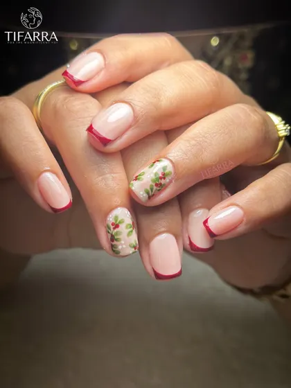 Minimal base, artisanal detail. A chic Christmas design with classic red French tips and accent nails featuring hand-painted holly.