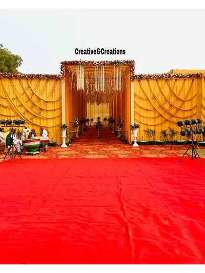 A grand entrance for a large-scale event. The wide red carpet leads into a beautifully draped yellow tent, ready to welcome hundreds of guests.