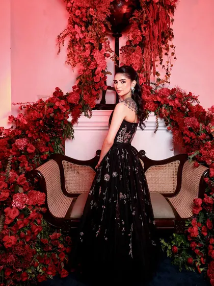 Set against a dramatic backdrop of red roses, this photo highlights the artistry of both the gown and the makeup. The look is pure couture, designed for a memorable fashion moment.