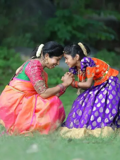 Creating matching outfits for mothers and daughters is a special joy. This heartwarming photo shows a mother in her custom saree and blouse, coordinated perfectly with her daughter's traditional pattu pavadai.