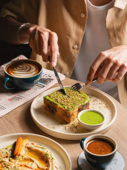 A customer cutting into a slice of pistachio toast at a cafe. This action shot makes the viewer feel like they are part of the experience.
