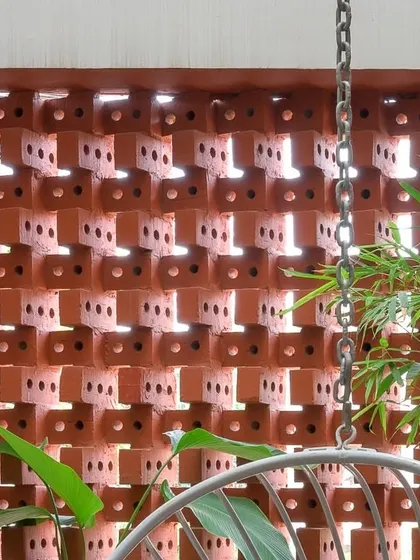 The brick screen viewed from the interior balcony, with a rain chain in the foreground. This space is designed to feel like a semi-outdoor verandah.