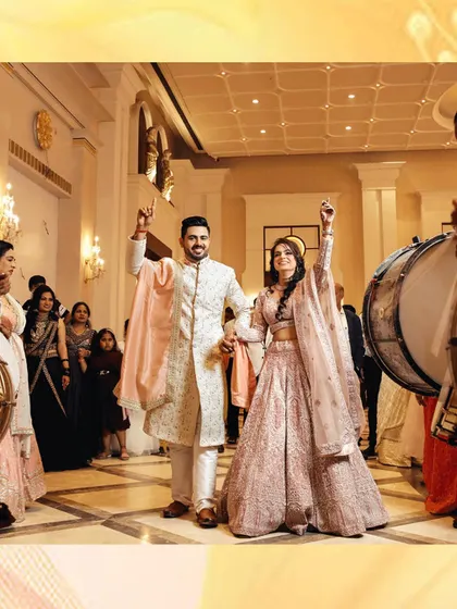 The grand entrance of the couple at their sangeet or engagement party, surrounded by dhol players and celebrating family. This shot captures the energy and excitement of the moment.