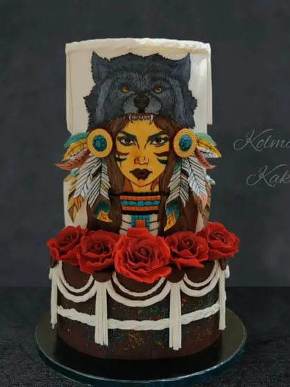 I love when a cake becomes a canvas. This two-tiered cake features a hand-painted Native American portrait, complemented by edible wafer paper feathers and a base of handmade sugar roses.