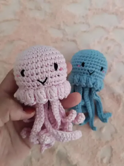Holding the pink jellyfish to show its size relative to the blue one. I can make them as tiny charms or larger plushies.