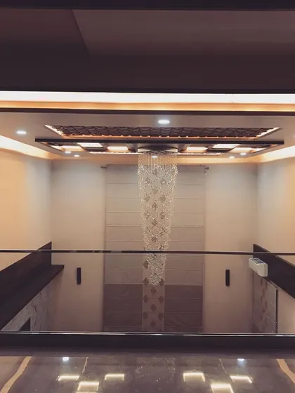 Looking down from the first-floor gallery into the formal living area. The design emphasizes vertical space, with the magnificent chandelier serving as the central jewel of the home's interior.