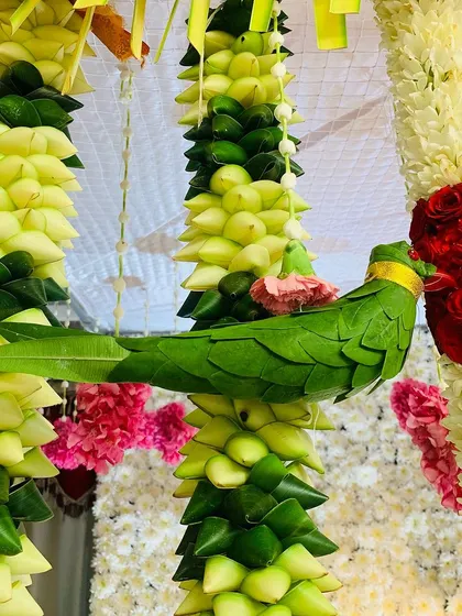 Our commitment to authenticity is in every detail. This close-up shows a parrot handcrafted entirely from fresh green leaves, a unique element we add to our traditional thorans and backdrops.