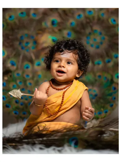 A joyful shot of the baby smiling during the little Murugan themed photoshoot.
