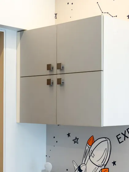 A close-up of the overhead storage cabinets above the study desk, showing the simple, modern hardware.