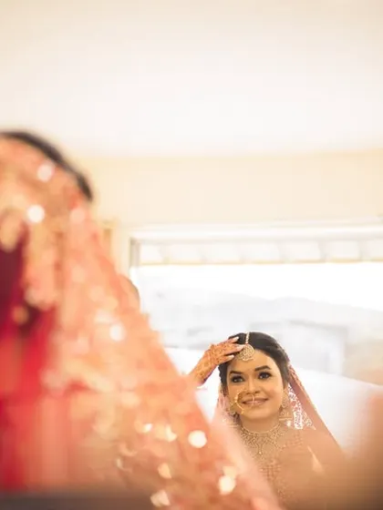 A creative shot of the bride looking at her reflection, full of anticipation for the day ahead.