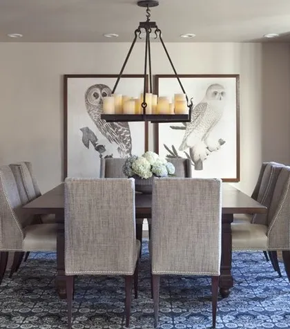 A classic dining room with a rustic wooden china cabinet, fabric-upholstered chairs, and unique artwork, creating a warm and inviting atmosphere.