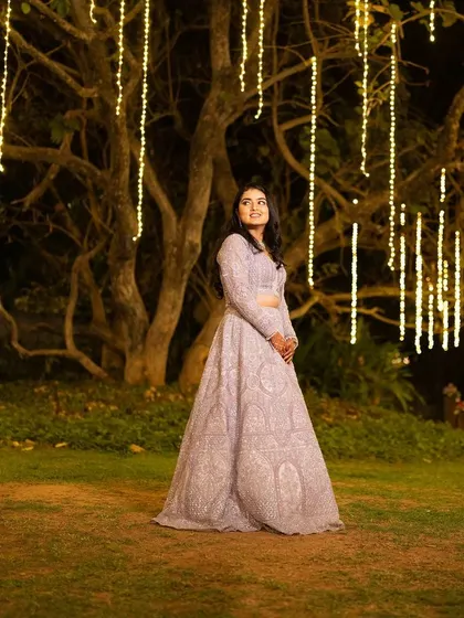 Shubha at her Sangeet, set against a backdrop of beautiful fairy lights. Her makeup is designed to glow in the evening ambiance.