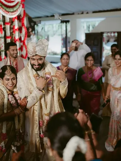 The groom's triumphant and joyful entrance into the wedding hall, surrounded by cheering family and friends.