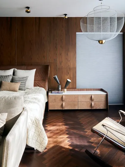 This bedroom in the Baid Residence is a tranquil retreat, filled with natural light. The space features a MOOOI light from Lightbox, a classic rocking chair from B&B Italia, and custom furniture from Alsorg.