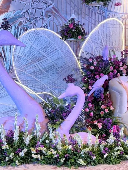 A close-up of the sculptural swans, nestled among a bed of purple and white flowers, adding an artistic touch to the decor.
