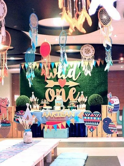 A "Wild One" tribal-themed birthday party. The decor featured a grass wall backdrop, dreamcatchers, and cute tribal animal cutouts for a fun and bohemian vibe.