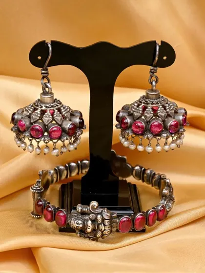 The jhumkha earrings and bracelet from the red stone set, arranged to showcase their complementary designs.