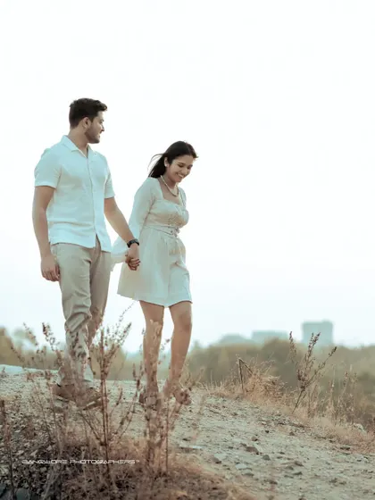 A candid moment of laughter and movement as the couple navigates a rustic path. This pre-wedding photo captures their joyful and easy connection.