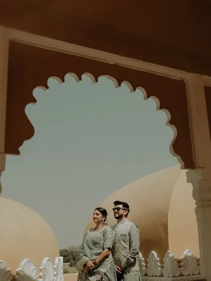 A wide shot that captures both the couple and the stunning scenery. Posing them between the pillars frames them perfectly, with the palace domes in the background telling the story of their destination wedding.