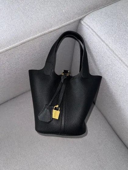 The HerCharm Bucket Bag in classic black. A must-have for any collection, this black version is sleek, versatile, and always in style.
