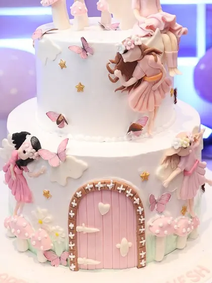 Even the cake is part of the story. This two-tiered masterpiece is adorned with intricate fairy figures, butterflies, and a magical door, perfectly matching the fairyland party theme.