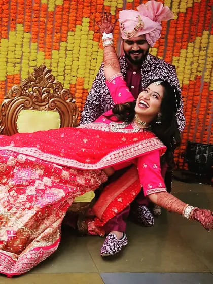 The joy of a wedding day is infectious. This happy couple is celebrating their mehndi ceremony, and you can see the bride's henna-adorned hands as she shares a joyful moment with her partner.