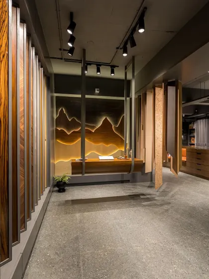 A wide shot of the showroom's main corridor, flanked by a wall of veneer samples and the suspended art installation.