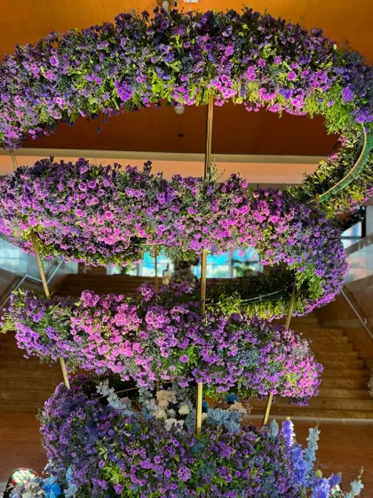 A magnificent spiral floral installation in shades of lavender and purple serves as a stunning centerpiece in the reception hall, showcasing my ability to create large-scale, artistic floral sculptures.