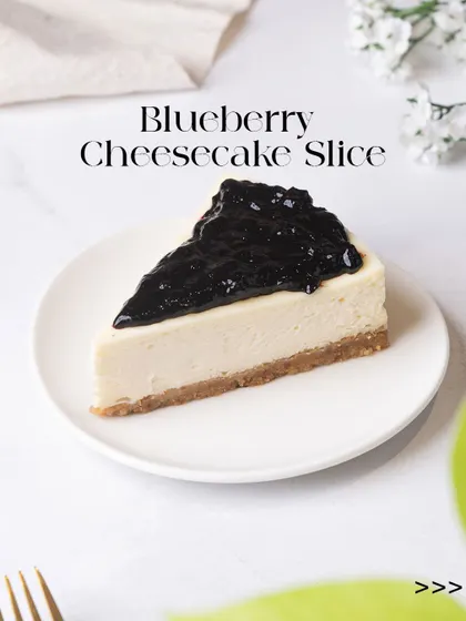 A classic Blueberry Cheesecake slice, featuring a creamy, rich filling on a crisp biscuit base, generously topped with a sweet blueberry compote. It's a bestseller for a reason.