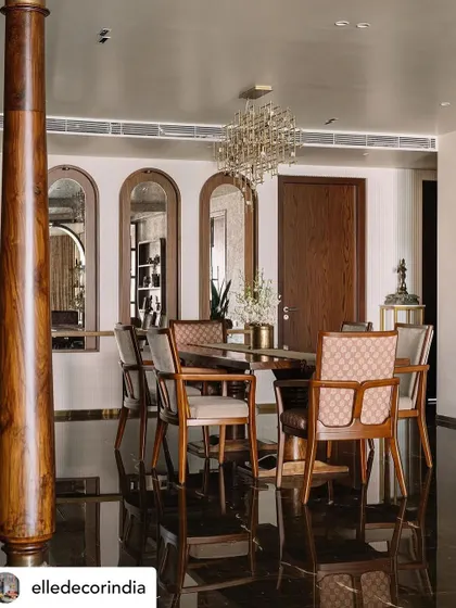 In the dining area, which lacked natural light, I used arched mirrors to reflect light from the living room balcony. The custom elephant-leg dining table and a contemporary chandelier create an elegant space for family meals, flanked by a traditional wooden pillar.