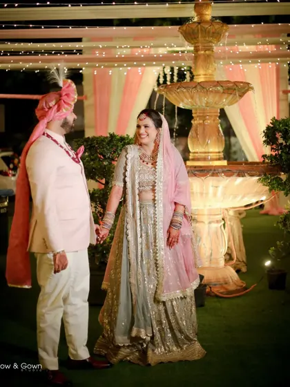 A sweet portrait of the couple on their wedding day, standing by a fountain. The soft lighting and their gentle hold create a romantic and serene atmosphere.
