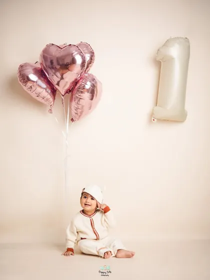A simple and modern first birthday shoot. The neutral tones and heart-shaped balloons create a chic and timeless portrait to celebrate year one.