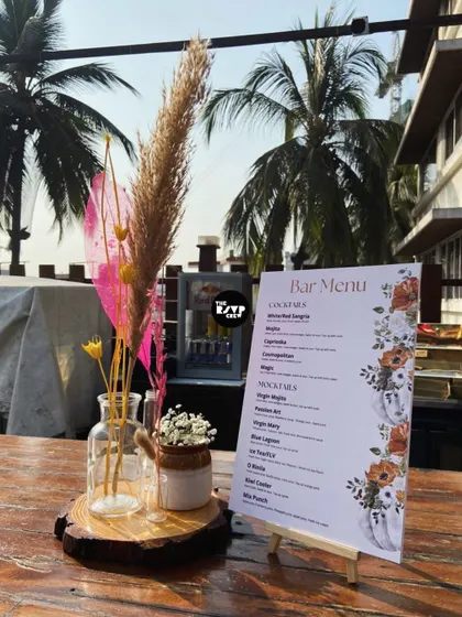 A chic and rustic centerpiece for an outdoor event, featuring a bar menu, dried pampas grass, and a wooden slice base.