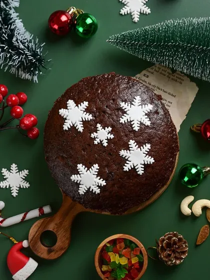 A classic Christmas scene featuring our eggless snowflake plum cake. It's the perfect centerpiece for your holiday table, surrounded by festive decorations.