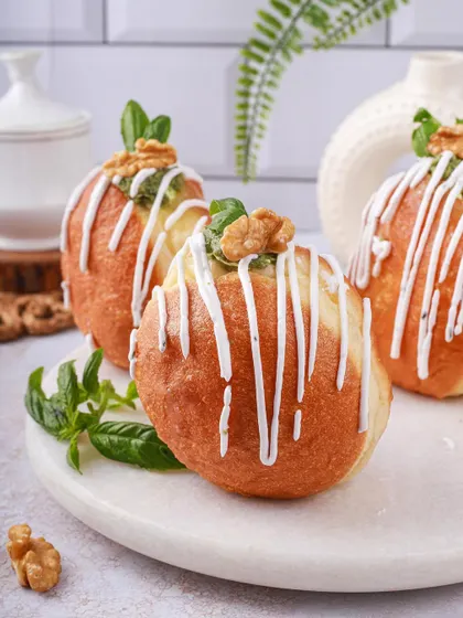 Savory pesto and walnut bombolonis with a white chocolate drizzle, offering a unique twist on the classic donut.