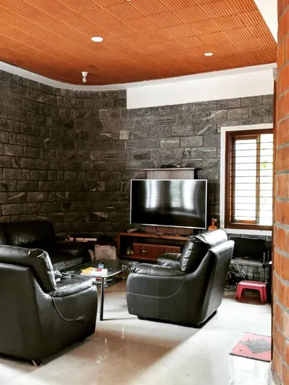 A cozy TV lounge area with a curved brick wall opposite a dark stone wall, creating a den-like atmosphere.