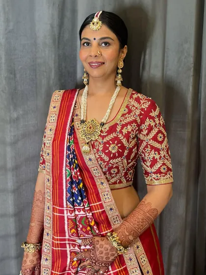 The final look of the client with her Patola saree and classic bun. This hairstyle is perfect for showcasing heavy, traditional jewelry.