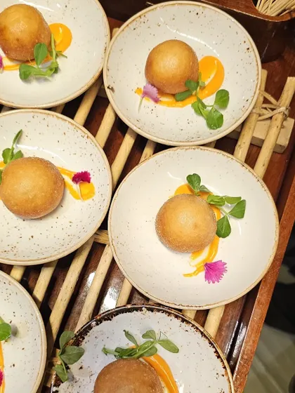 Individually plated golden-fried appetizers, garnished with microgreens and edible flowers.
