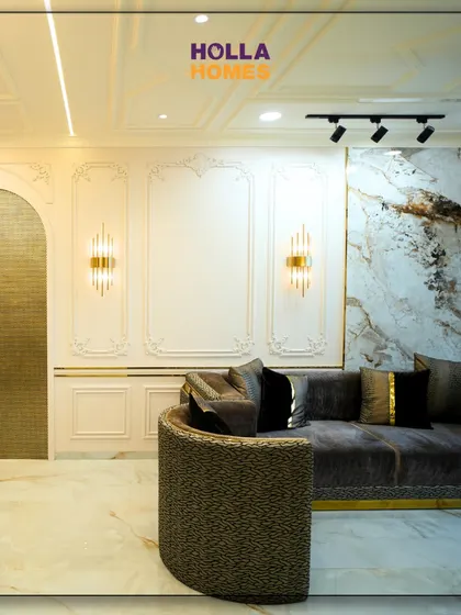 This living room showcases a Parisian theme with its elegant wall mouldings, gold accents, and a curved sofa. It’s a perfect blend of classic beauty and modern luxury.