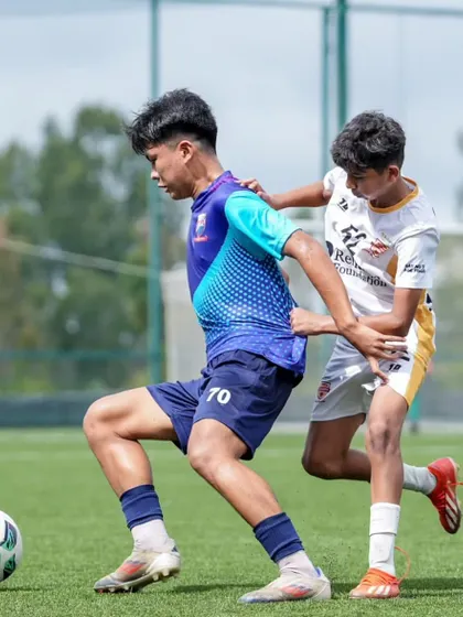 A player shields the ball from an opponent, demonstrating strength and game awareness.
