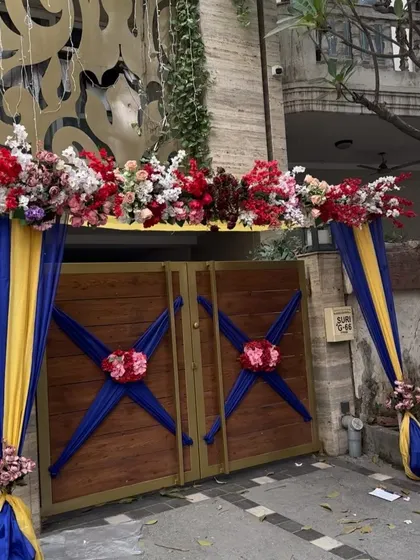 A closer look at the floral arrangement on the wedding house gate. The mix of red, white, and yellow flowers creates a vibrant and welcoming look.