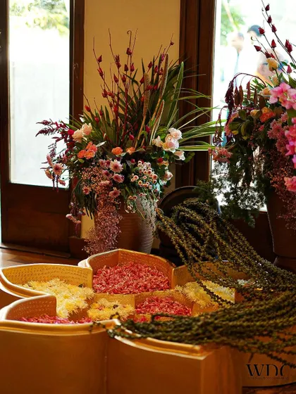 A beautiful display of fresh flowers and petals in custom-designed wooden trays, ready for guests to use during the celebration.