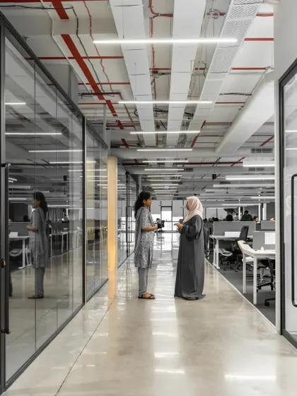 The main corridor at the Netenrich office, with exposed ceilings and ductwork, embraces an honest, industrial aesthetic. Glass-walled meeting rooms maintain a sense of openness and transparency, reflecting a culture of collaboration and straightforward communication.