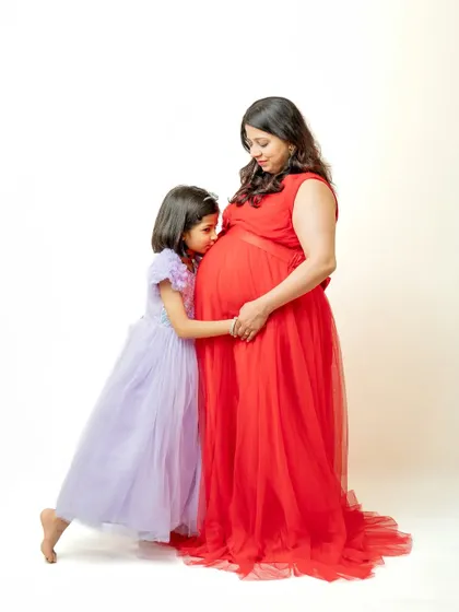 A truly precious moment between a mother and her daughter, who is giving the baby bump a sweet kiss. This image beautifully captures the love and anticipation of a big sister-to-be.