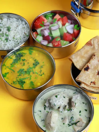 A light yet satisfying meal of creamy white chicken curry, dal, rice, roti, and fresh salad, all packed in our signature steel tiffins.